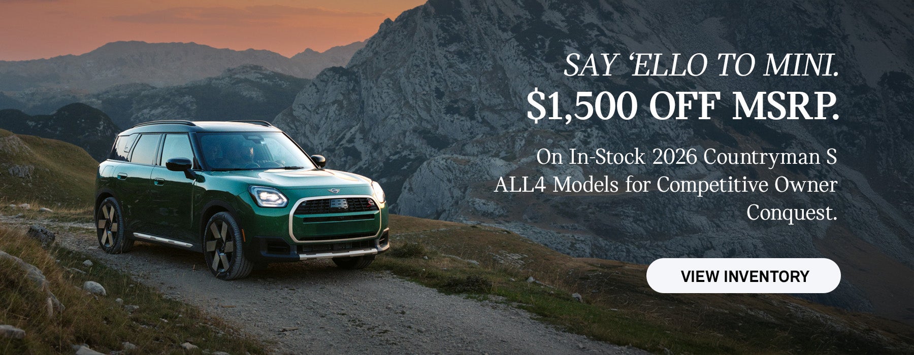 Front passenger side view of a MINI Countryman driving on a mountainous road.