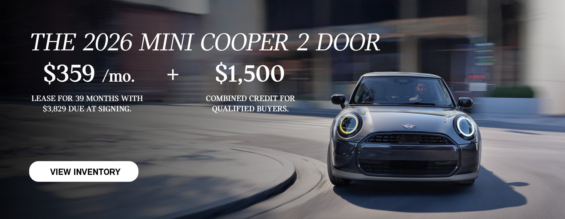 Front view of man driving grey MINI 2Door down a curved city street.