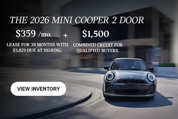 Front view of man driving grey MINI 2Door down a curved city street.