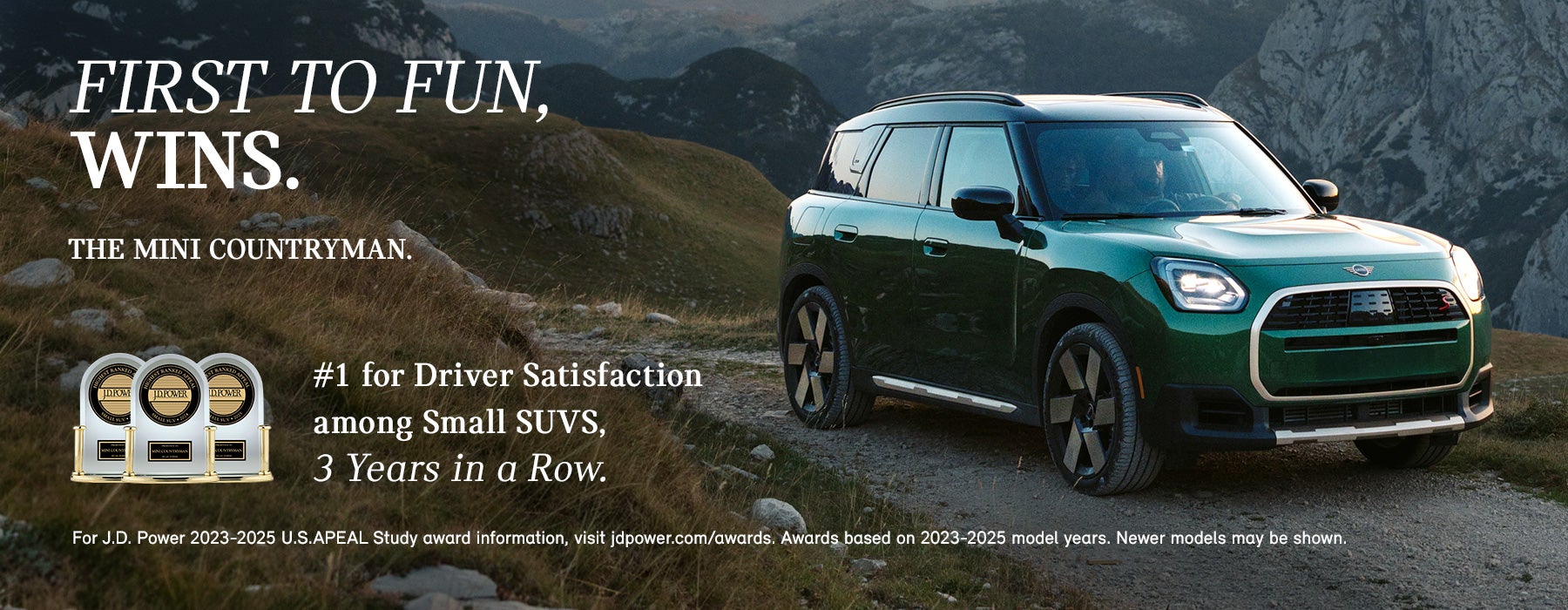 Front passenger side view of a green MINI Countryman driving on a mountainous road.