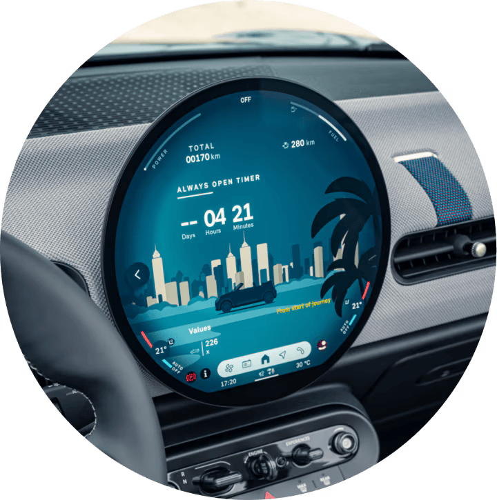 Close-up of the MINI OLED Display with a green concrete wall outside the front windshield.