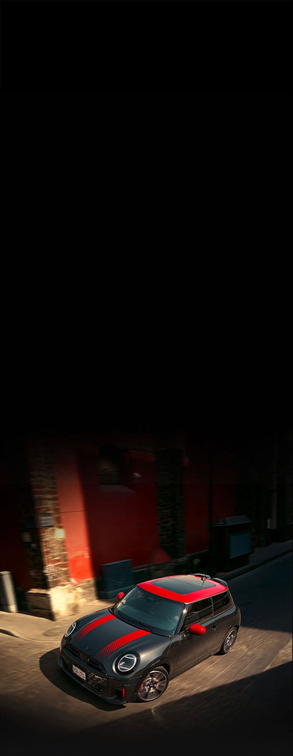 Bird’s-eye view of the MINI JCW 2 Door turning a corner on a cobblestone street.